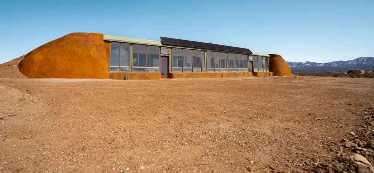 A Refuge model Earthship in Taos, New Mexico: earth-bermed walls, a long glass front and solar panels